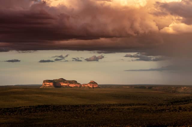 Duas formações rochosas de arenito brilhando em âmbar sob um céu tempestuoso dramático sobre a savana do Cerrado em um passeio pelo Jalapão no Brasil
