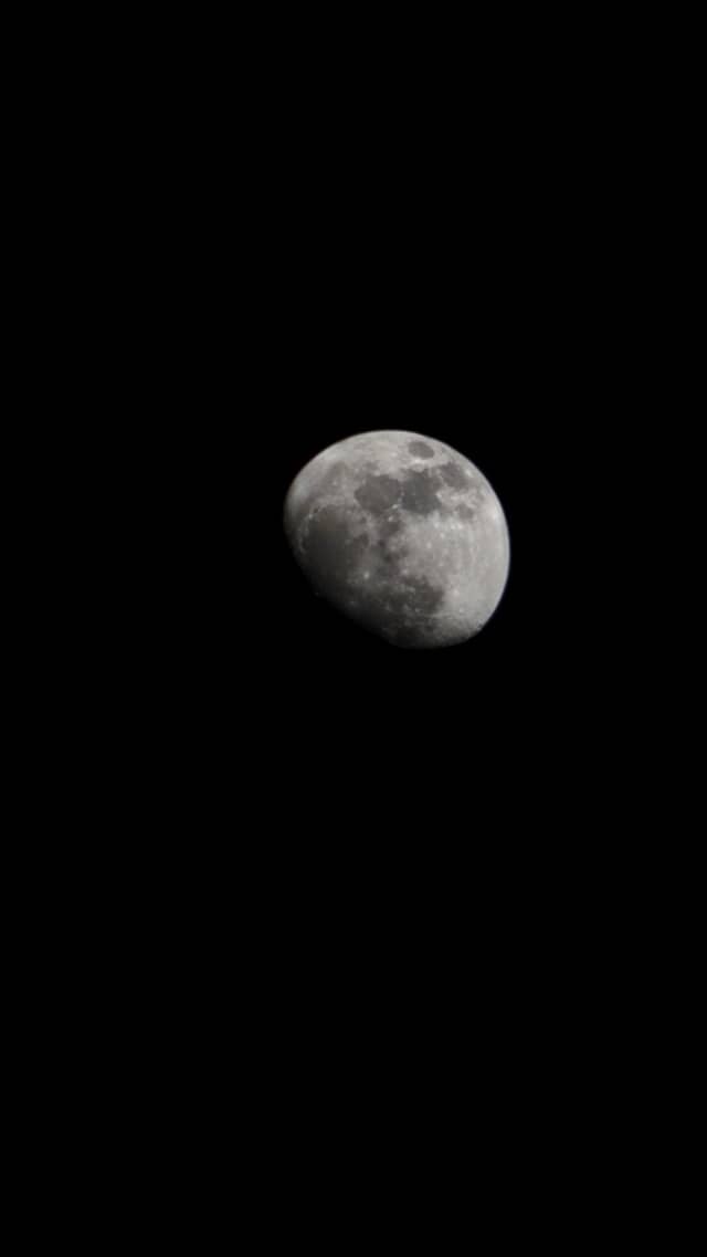 Primo piano teleobiettivo di una luna gibbosa calante contro un cielo notturno nero pece, avvistata durante una spedizione di trekking in Brasile