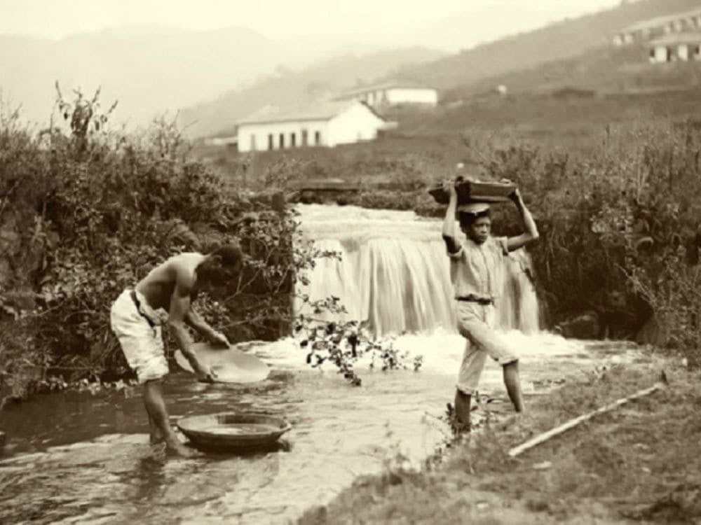 Fotografia storica color seppia di due minatori al lavoro nella ricerca di diamanti in un fiume della regione della Chapada Diamantina.