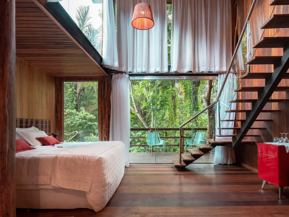 A luxury room with a large glass window facing the forest at Mirante do Gavião in the Amazon rainforest.