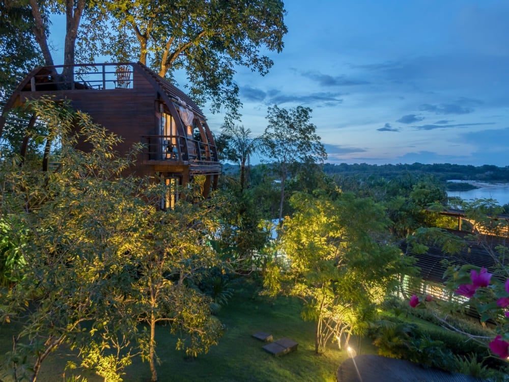 The unique wooden architecture of Mirante do Gavião lodge illuminated at dusk, representing one of the best Amazon jungle lodges in Brazil.