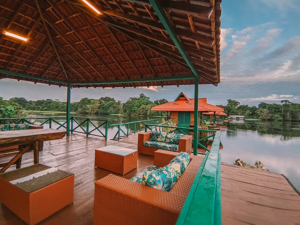 A wooden deck with comfortable sofas overlooking the floating bungalows and river at Uakari Lodge in Brazil.