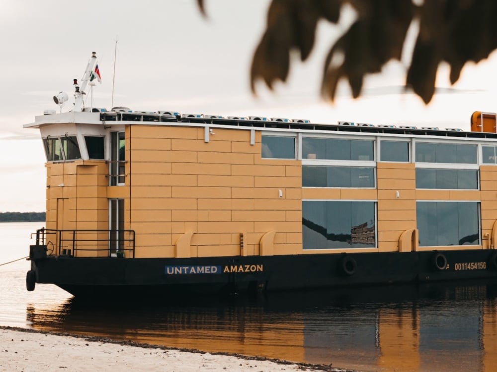 La barca Untamed Amazon, dal design moderno con scafo giallo, nota per essere una crociera sostenibile alimentata a energia solare.