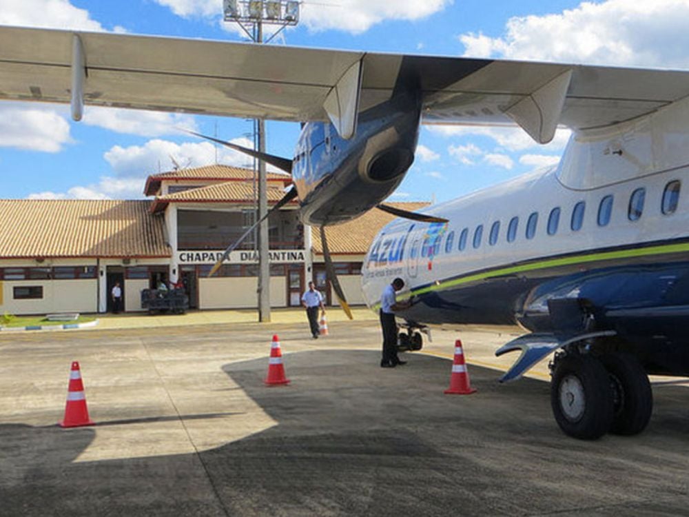 Aereo della compagnia Azul fermo sulla pista dell'aeroporto della Chapada Diamantina. Alcuni addetti lavorano vicino al velivolo in una giornata di sole.