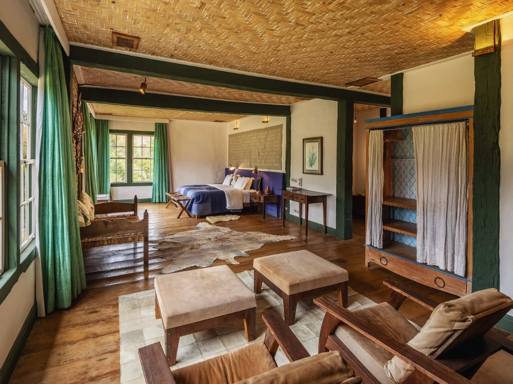 Spacious rustic bedroom with a large bed, wooden floors, and green accents at Ibiti Project.