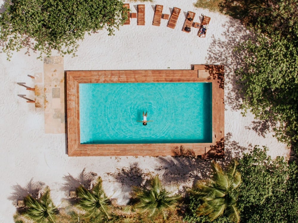 Aerial view of a person swimming in a rectangular pool at La Ferme de Georges inn.