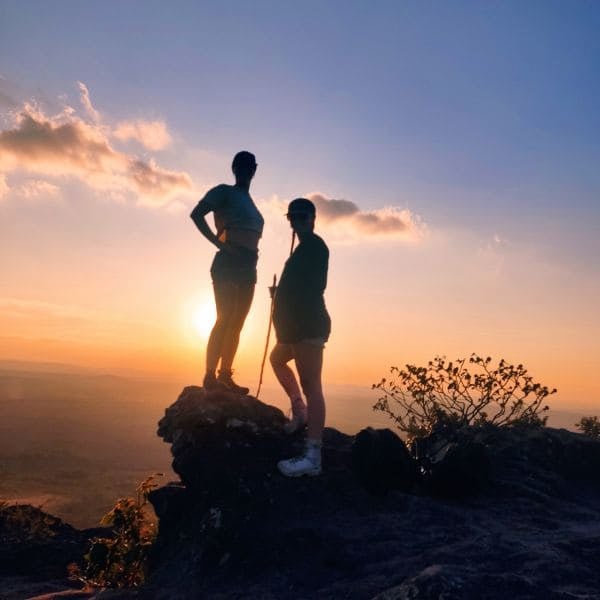 Twee wandelaars als silhouet op een rots bij zonsondergang in de Chapada Diamantina, Brazilië.