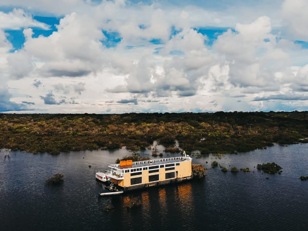 Vista aérea del barco de lujo Untamed anclado en el río Negro, rodeado por la selva amazónica inundada.