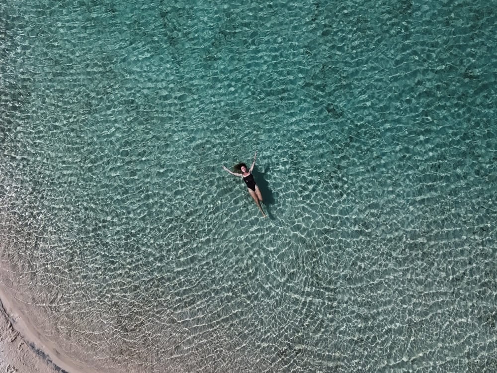 Luchtfoto van een vrouw die op haar rug drijft in het heldere turquoise water van Lagoa Azul bij Barreirinhas