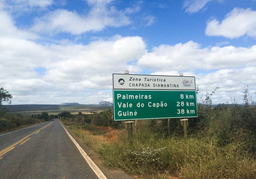 Ein grünes Straßenschild für die Touristenzone Chapada Diamantina, das die Entfernungen nach Palmeiras, Vale do Capão und Guiné anzeigt. Ein grünes Straßenschild für die Touristenzone Chapada Diamantina, das die Entfernungen nach Palmeiras, Vale do Capão und Guiné anzeigt.