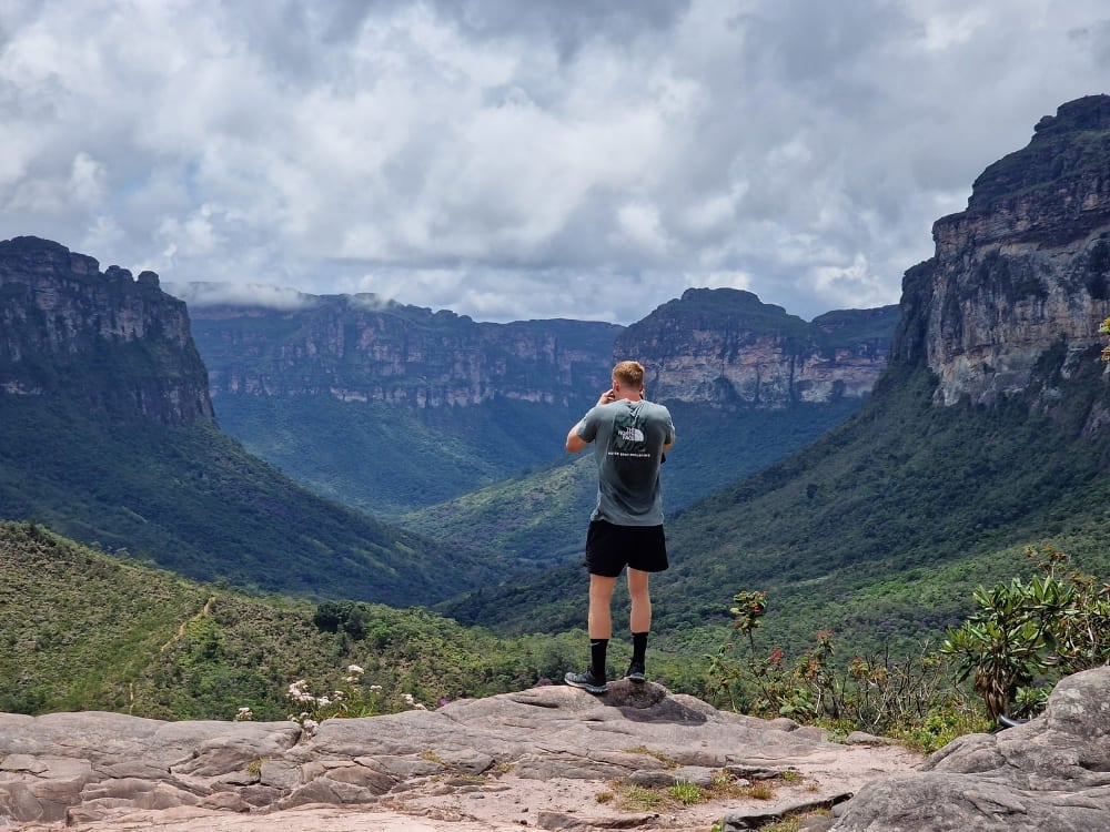 Ein Wanderer steht auf einem Felsvorsprung und fotografiert die weitläufigen grünen Täler und Tafelberge. Ein Wanderer steht auf einem Felsvorsprung und fotografiert die weitläufigen grünen Täler und Tafelberge.