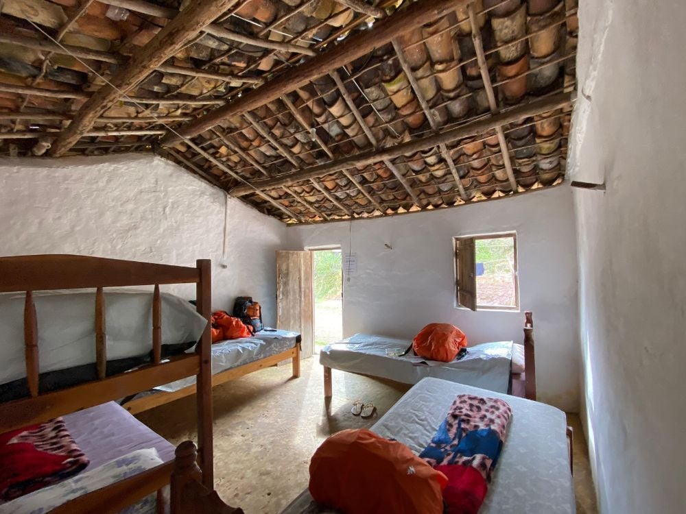 Ein Gemeinschaftsschlafzimmer in einer Gastfamilie mit Holzbetten, Schlafsäcken und einer rustikalen Decke aus freiliegenden Ziegeln und Holz. Ein Gemeinschaftsschlafzimmer in einer Gastfamilie mit Holzbetten, Schlafsäcken und einer rustikalen Decke aus freiliegenden Ziegeln und Holz.