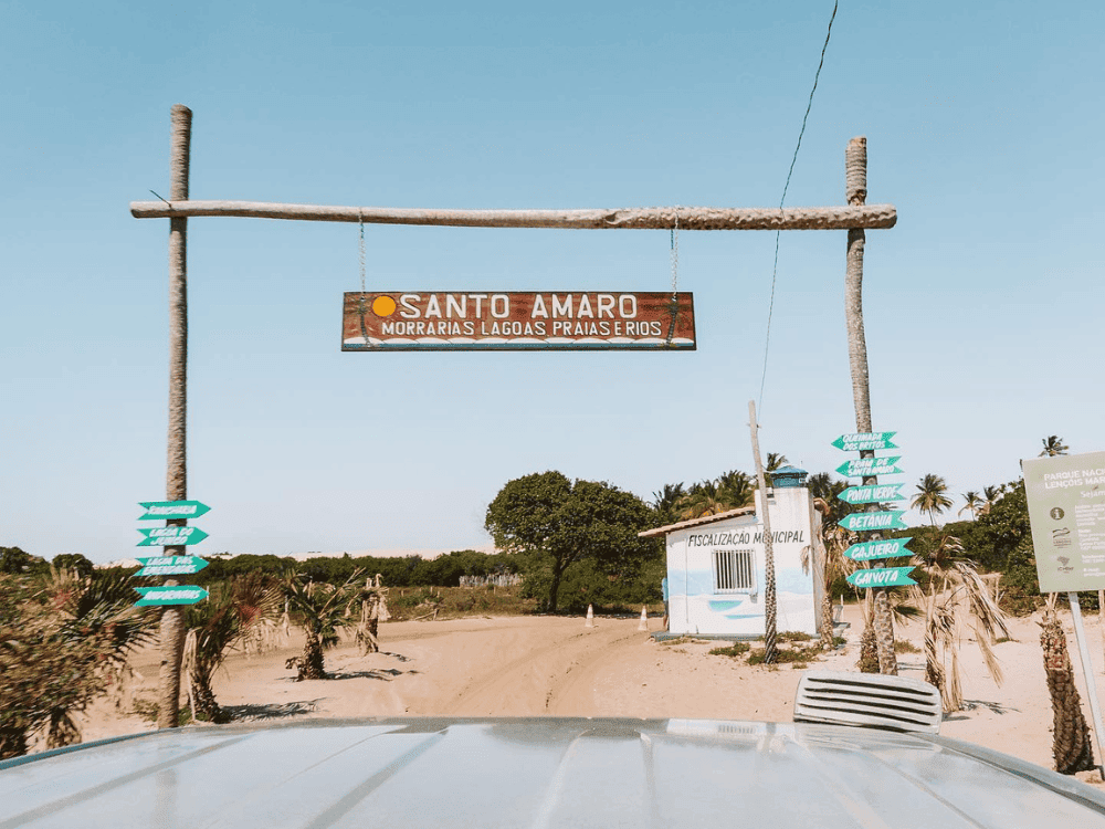 Portale rustico con un cartello di legno con la scritta Santo Amaro Morvanas Lagoas Prajasthios, sopra una strada sabbiosa. Portale rustico con un cartello di legno con la scritta Santo Amaro Morvanas Lagoas Prajasthios, sopra una strada sabbiosa.