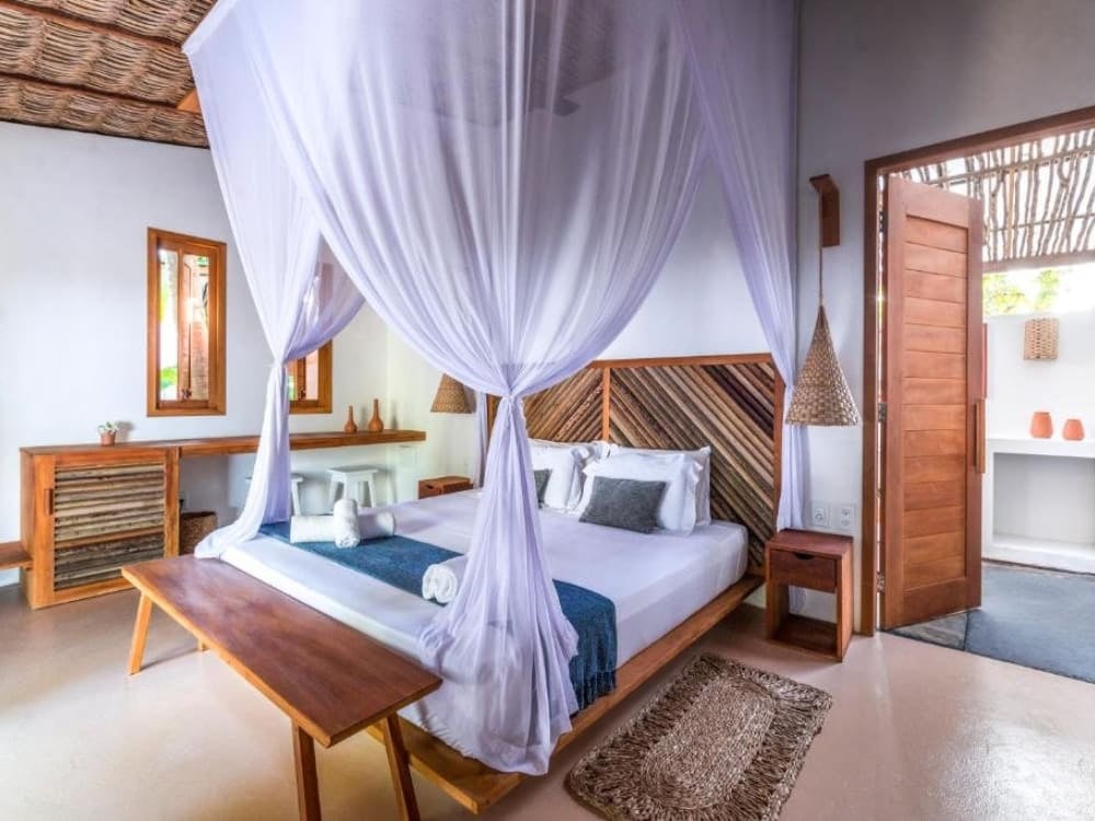 Interno elegante e luminoso di uno chalet della pousada Muita Paz, con al centro un letto matrimoniale coperto da un'ampia zanzariera trasparente. Interno elegante e luminoso di uno chalet della pousada Muita Paz, con al centro un letto matrimoniale coperto da un'ampia zanzariera trasparente.