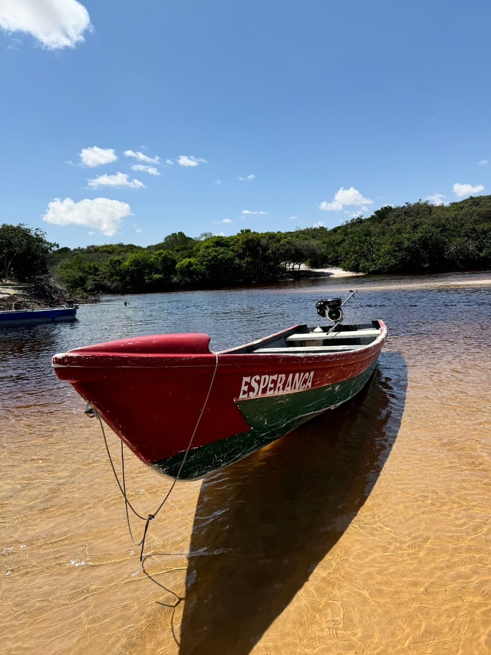 Una barca rossa e verde di nome Esperanca sulla riva sabbiosa delle acque scure del fiume Preguiças. Una barca rossa e verde di nome Esperanca sulla riva sabbiosa delle acque scure del fiume Preguiças.