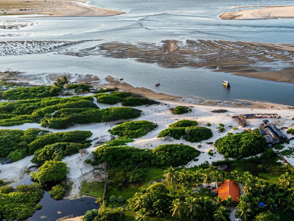 Veduta aerea di Atins, con la vegetazione verde, i banchi di sabbia e l'incontro fra le acque del fiume Preguiças e l'oceano. Veduta aerea di Atins, con la vegetazione verde, i banchi di sabbia e l'incontro fra le acque del fiume Preguiças e l'oceano.