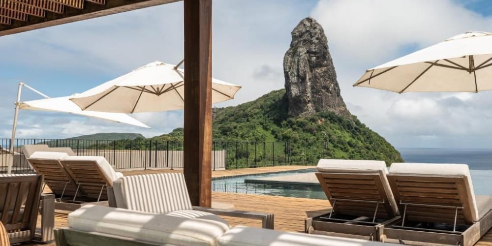 Terrazza di un hotel di lusso con piscina e lettini comodi affacciati sull'iconico Morro do Pico, in Brasile. Terrazza di un hotel di lusso con piscina e lettini comodi affacciati sull'iconico Morro do Pico, in Brasile.