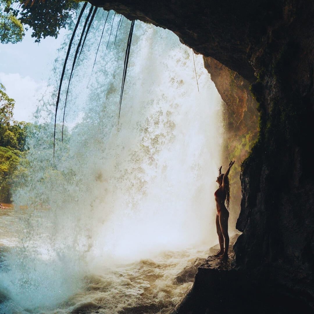 Un viaggiatore in piedi dietro una cascata potente nella foresta amazzonica, con le braccia alzate. Un viaggiatore in piedi dietro una cascata potente nella foresta amazzonica, con le braccia alzate.