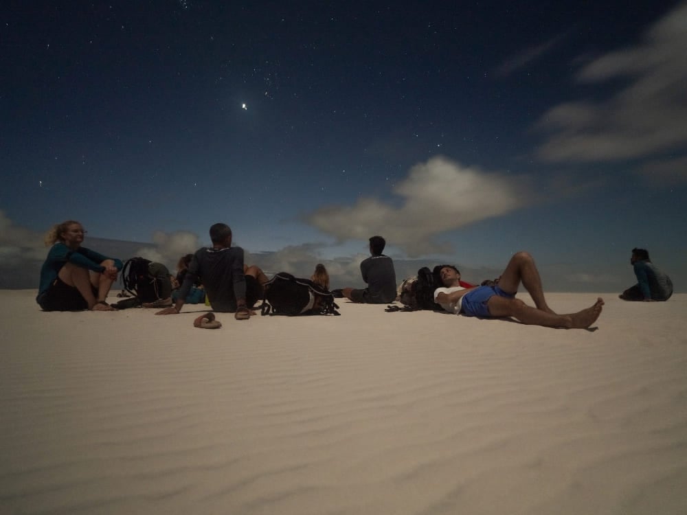 Un gruppo di viaggiatori riposa sulle dune di sabbia sotto un cielo stellato, dopo una giornata intera passata a esplorare i Lençóis Maranhenses. Un gruppo di viaggiatori riposa sulle dune di sabbia sotto un cielo stellato, dopo una giornata intera passata a esplorare i Lençóis Maranhenses.