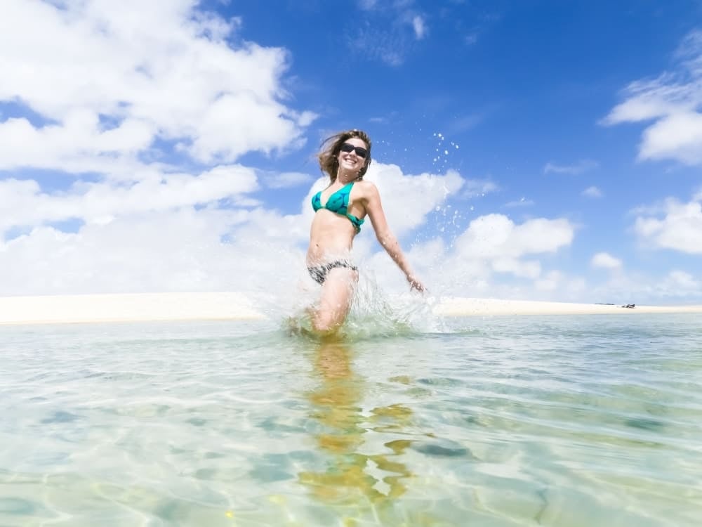 Una donna sorridente si gode un bagno rinfrescante in una laguna di acqua dolce cristallina, in una giornata di sole nei Lençóis Maranhenses. Una donna sorridente si gode un bagno rinfrescante in una laguna di acqua dolce cristallina, in una giornata di sole nei Lençóis Maranhenses.