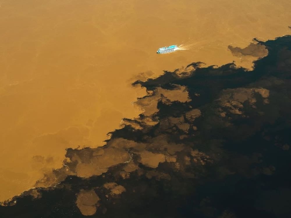 Veduta aerea della linea di separazione netta dove il Rio Negro nero incontra il Rio Solimões marrone. Veduta aerea della linea di separazione netta dove il Rio Negro nero incontra il Rio Solimões marrone.