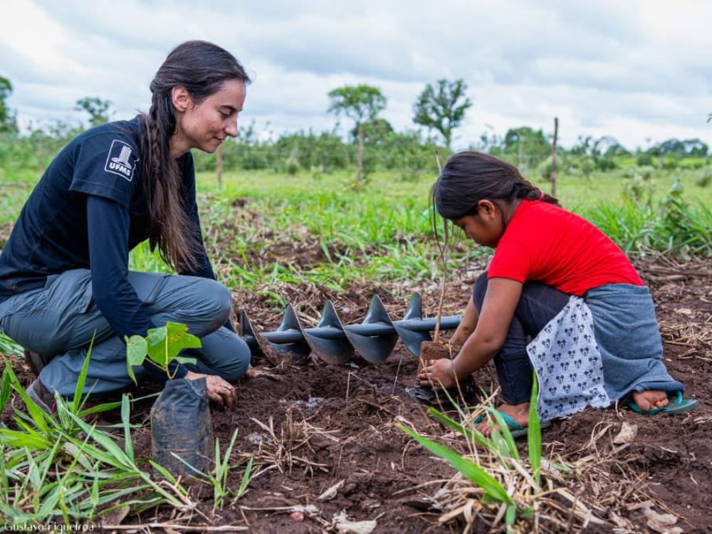 Una donna e una bambina inginocchiate nella terra mentre piantano un alberello nelle zone umide del Pantanal. Una donna e una bambina inginocchiate nella terra mentre piantano un alberello nelle zone umide del Pantanal.