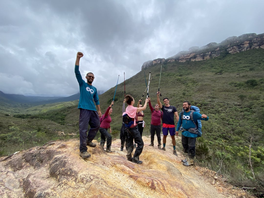 Un gruppo di escursionisti e una guida di PlanetaEXO festeggiano con le braccia alzate su una cima rocciosa, circondati da montagne verdi sotto un cielo nuvoloso. Un gruppo di escursionisti e una guida di PlanetaEXO festeggiano con le braccia alzate su una cima rocciosa, circondati da montagne verdi sotto un cielo nuvoloso.