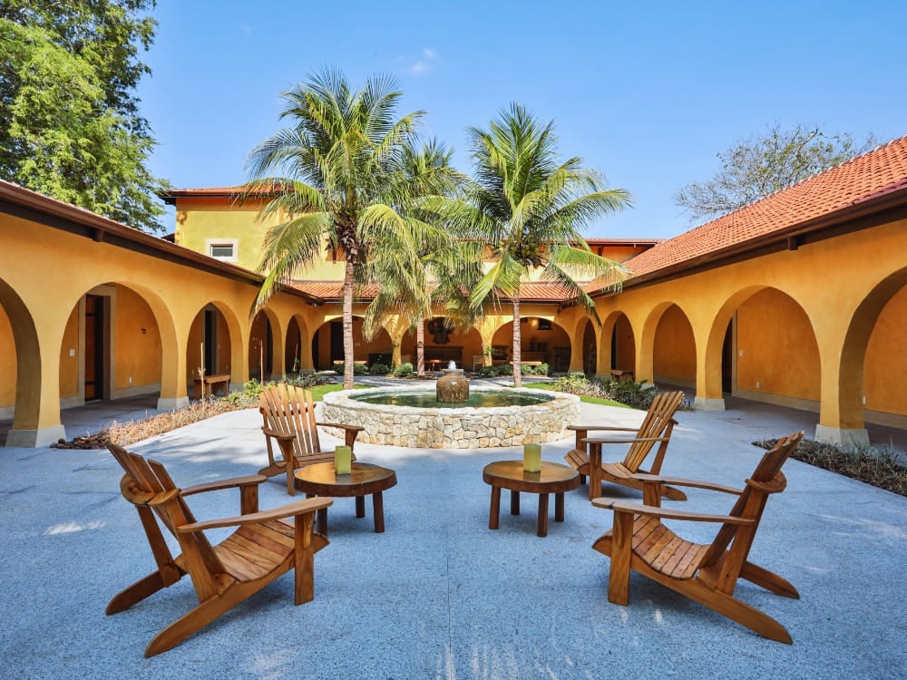 L'elegante cortile di uno dei tanti lodge del Pantanal, con archi gialli e sedie di legno intorno a una fontana. L'elegante cortile di uno dei tanti lodge del Pantanal, con archi gialli e sedie di legno intorno a una fontana.