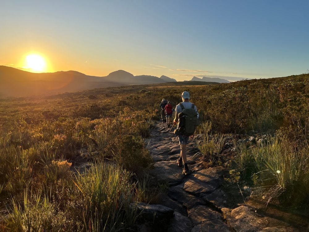 Un gruppo di escursionisti con lo zaino cammina su un sentiero roccioso verso le montagne, in un tramonto luminoso nella Chapada Diamantina. Un gruppo di escursionisti con lo zaino cammina su un sentiero roccioso verso le montagne, in un tramonto luminoso nella Chapada Diamantina.