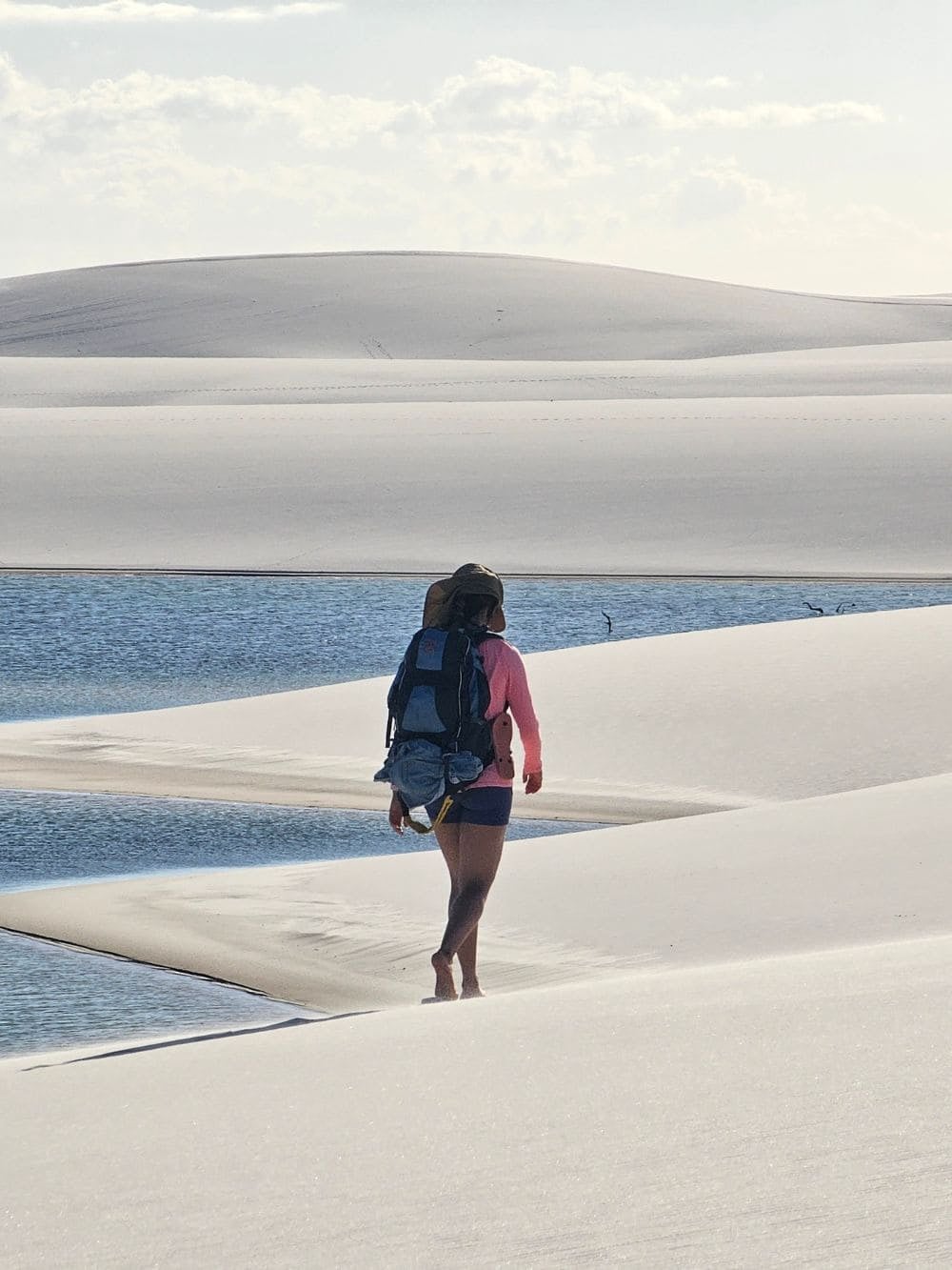 Un viaggiatore con lo zaino cammina scalzo lungo la riva di una laguna tranquilla a Santo Amaro. Un viaggiatore con lo zaino cammina scalzo lungo la riva di una laguna tranquilla a Santo Amaro.