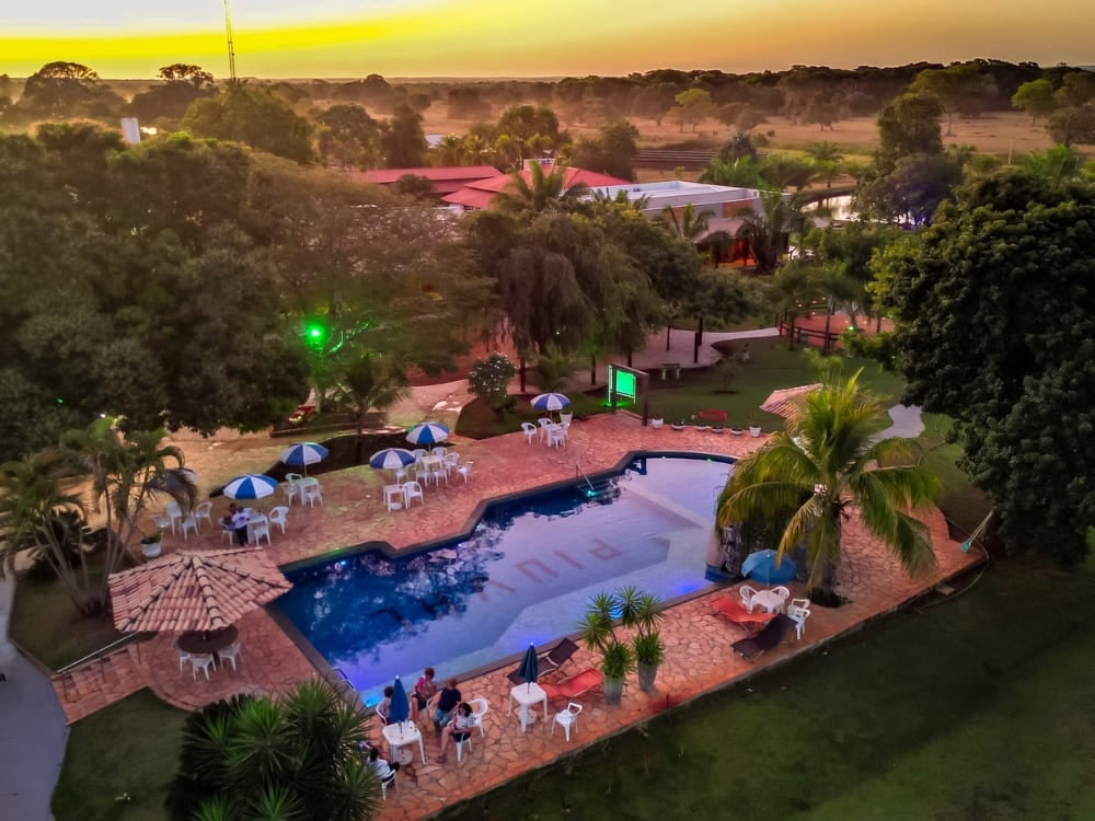 Guests relax near the outdoor swimming pool at Piuval lodge during a colorful sunset in the Northern Pantanal. Guests relax near the outdoor swimming pool at Piuval lodge during a colorful sunset in the Northern Pantanal.