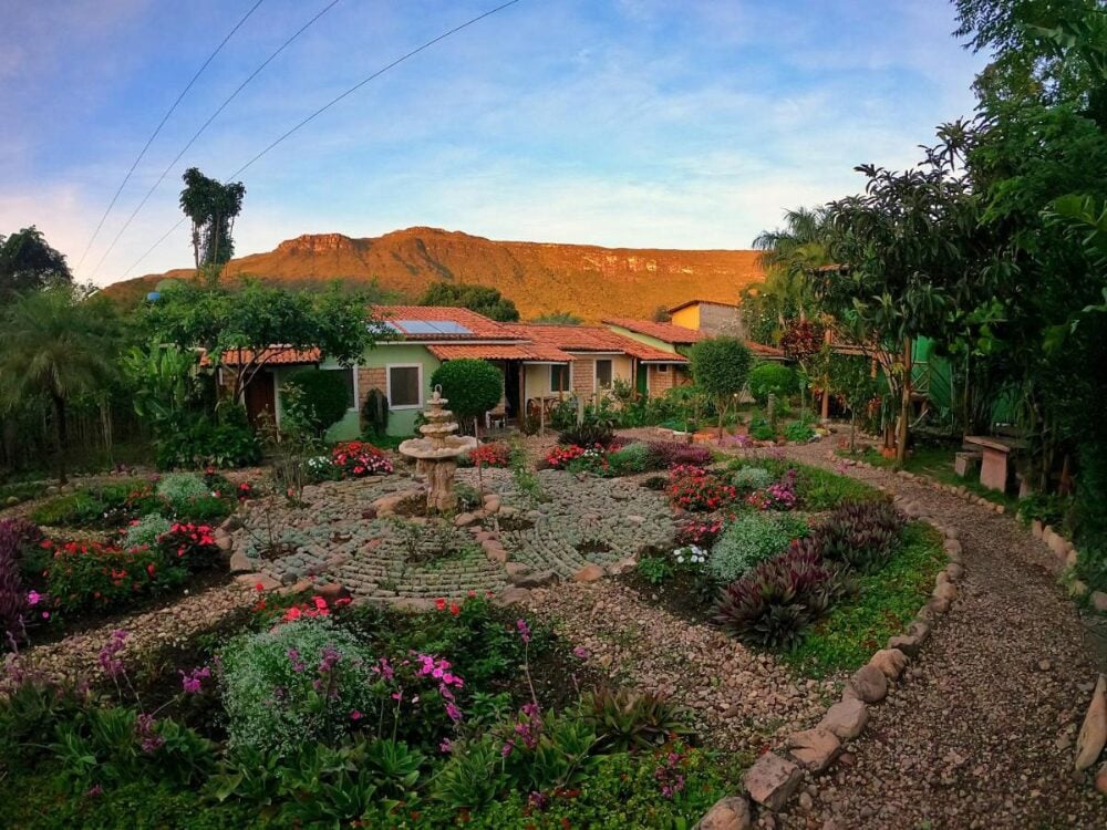 Giardino circolare ben tenuto con una fontana di pietra in un rifugio tranquillo, incorniciato dalle montagne verdi della Chapada Diamantina. Giardino circolare ben tenuto con una fontana di pietra in un rifugio tranquillo, incorniciato dalle montagne verdi della Chapada Diamantina.