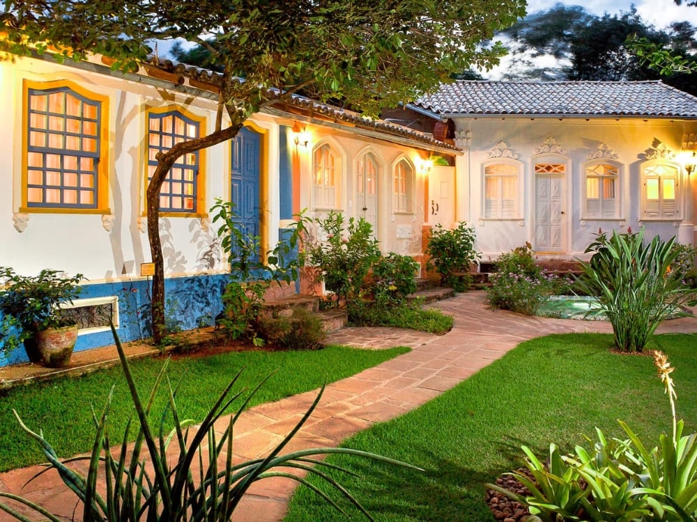 Cortile in stile coloniale della Pousada Vila Serrano a Lençóis, con pareti bianche e blu e giardini verdi e rigogliosi. Cortile in stile coloniale della Pousada Vila Serrano a Lençóis, con pareti bianche e blu e giardini verdi e rigogliosi.