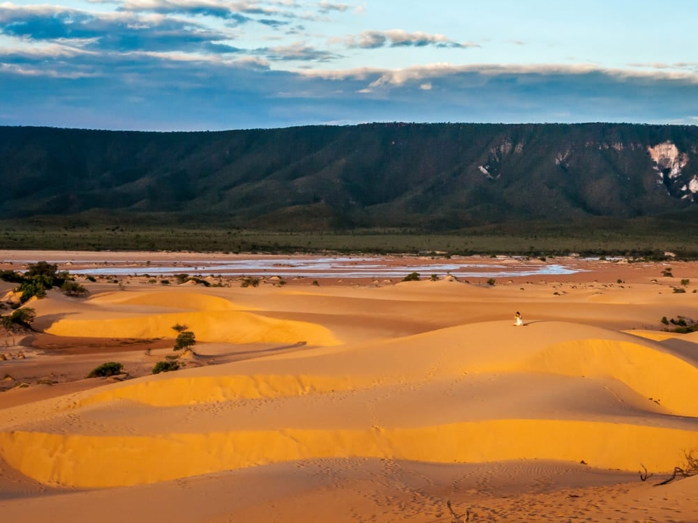 Un voyageur s'assoit sur les dunes de sable doré du Jalapão en regardant le coucher du soleil sur les montagnes. Un voyageur s'assoit sur les dunes de sable doré du Jalapão en regardant le coucher du soleil sur les montagnes.