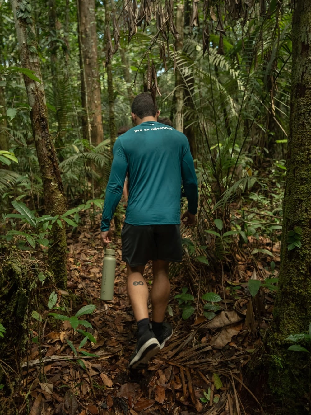Una viaggiatrice percorre un sentiero nel bosco circondata da alberi alti nella Foresta Amazzonica, un'attività tipica della stagione secca. Una viaggiatrice percorre un sentiero nel bosco circondata da alberi alti nella Foresta Amazzonica, un'attività tipica della stagione secca.