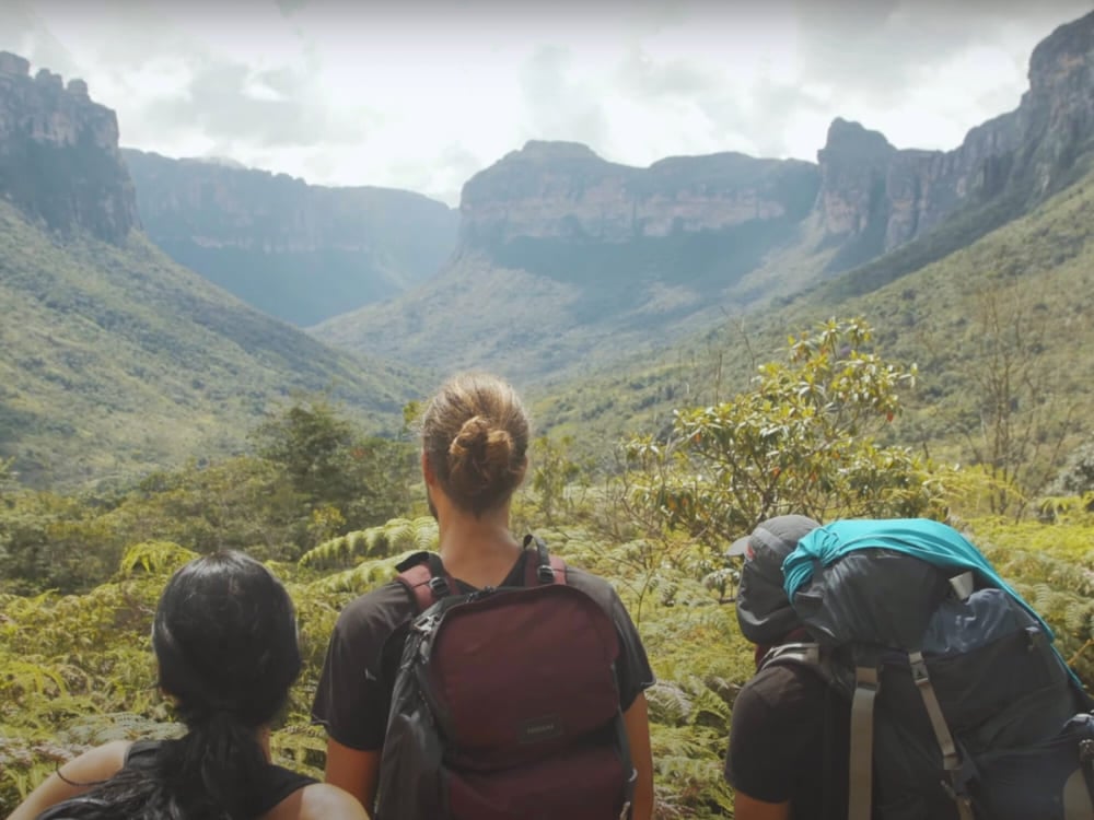 Tre viaggiatori con lo zaino osservano un'ampia valle verde nel cuore della Chapada Diamantina. Tre viaggiatori con lo zaino osservano un'ampia valle verde nel cuore della Chapada Diamantina.
