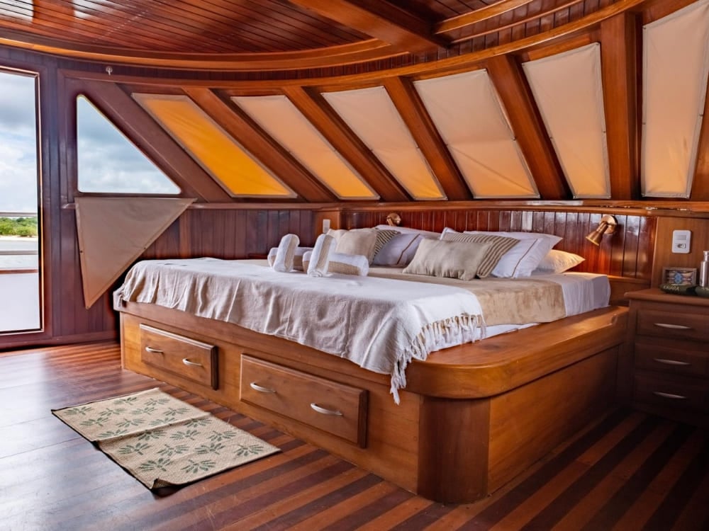 Large double bed with white sheets in a spacious cabin with a wooden ceiling on the cruise. Large double bed with white sheets in a spacious cabin with a wooden ceiling on the cruise.