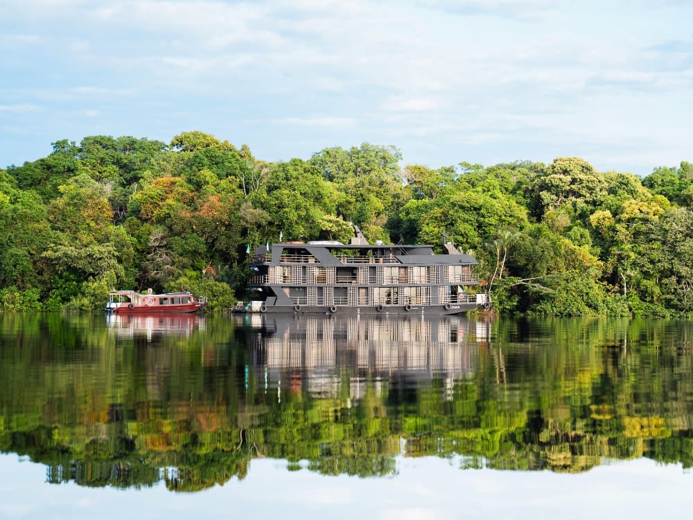 Large and luxurious river cruise ship reflected in the calm waters of an Amazon river. Large and luxurious river cruise ship reflected in the calm waters of an Amazon river.