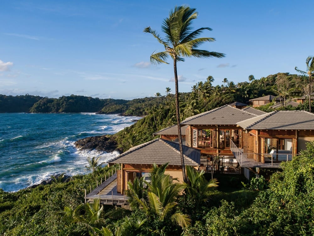 Luxurious villas with wooden roofs surrounded by palm trees on a cliff facing the sea. Luxurious villas with wooden roofs surrounded by palm trees on a cliff facing the sea.
