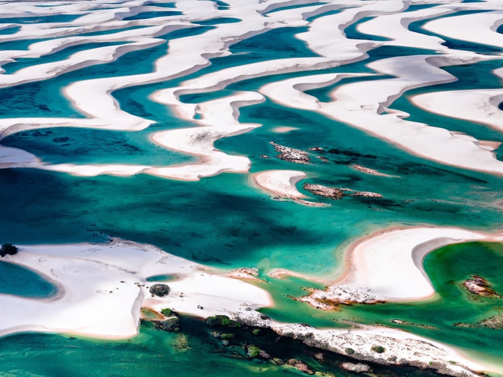 Aerial view of vibrant blue pools nestled among stark white sand dunes, highlighting the Lençóis Maranhenses best time to visit lagoons months. Aerial view of vibrant blue pools nestled among stark white sand dunes, highlighting the Lençóis Maranhenses best time to visit lagoons months.