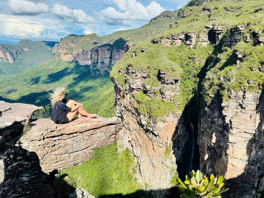 Avventuriera seduta sul bordo di una roccia che osserva i paesaggi verdi, vasti e aperti della Chapada Diamantina. Avventuriera seduta sul bordo di una roccia che osserva i paesaggi verdi, vasti e aperti della Chapada Diamantina.