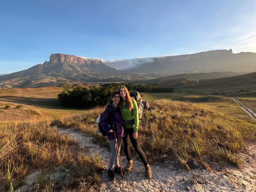 Due escursioniste sorridono insieme su un sentiero erboso con il maestoso Monte Roraima sullo sfondo. Due escursioniste sorridono insieme su un sentiero erboso con il maestoso Monte Roraima sullo sfondo.