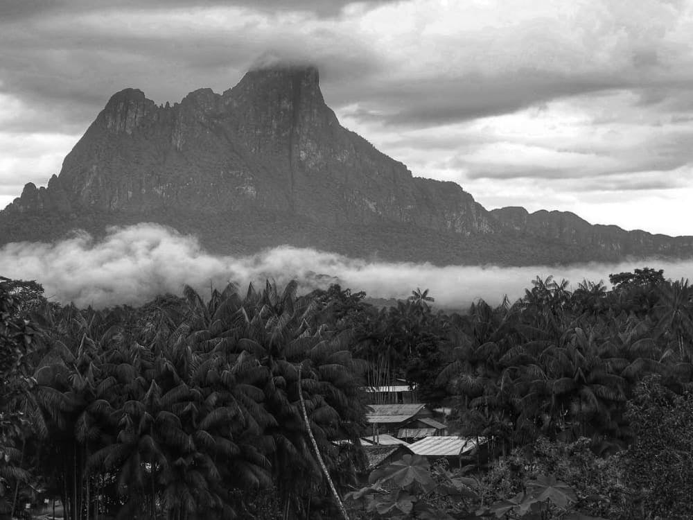Una veduta intensa del Pico da Neblina parzialmente coperto da nuvole basse e dense che si alzano sopra la volta della giungla. Una veduta intensa del Pico da Neblina parzialmente coperto da nuvole basse e dense che si alzano sopra la volta della giungla.