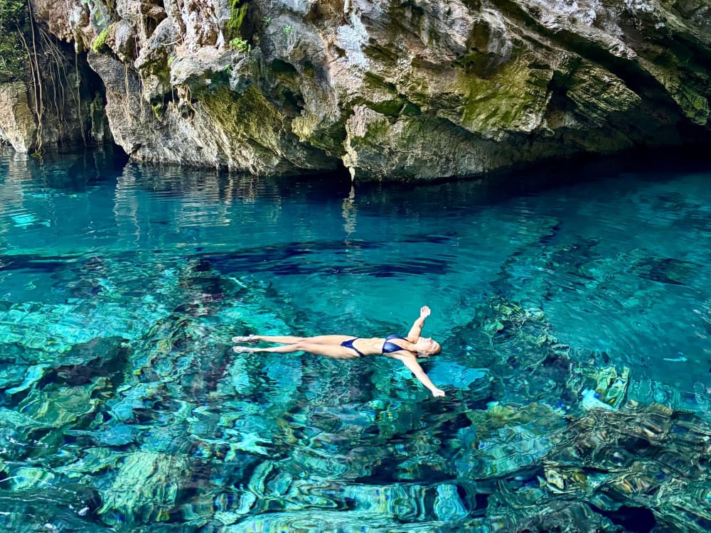 Donna in bikini che galleggia a braccia aperte nelle acque cristalline e turchesi di un fervedouro naturale circondato da rocce, nel Jalapão. Donna in bikini che galleggia a braccia aperte nelle acque cristalline e turchesi di un fervedouro naturale circondato da rocce, nel Jalapão.