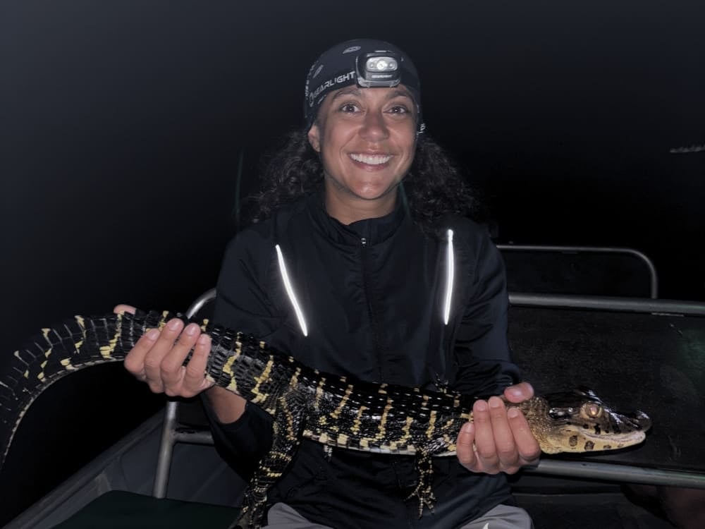 Samantha Sage sorride mentre tiene in mano un piccolo caimano durante un tour di ecoturismo notturno con guida, nell'Amazzonia brasiliana. Samantha Sage sorride mentre tiene in mano un piccolo caimano durante un tour di ecoturismo notturno con guida, nell'Amazzonia brasiliana.