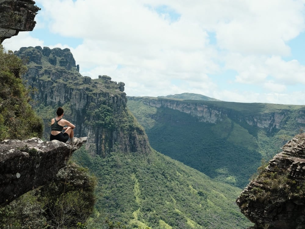 Donna seduta sul bordo di una parete rocciosa che contempla l'immensità verde degli altopiani e delle valli della Chapada Diamantina. Donna seduta sul bordo di una parete rocciosa che contempla l'immensità verde degli altopiani e delle valli della Chapada Diamantina.