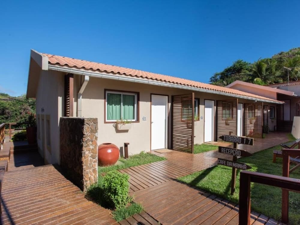 Passerella in legno che porta alle camere rustiche di una guest house, con porte bianche e piccoli giardini, a Fernando de Noronha. Passerella in legno che porta alle camere rustiche di una guest house, con porte bianche e piccoli giardini, a Fernando de Noronha.