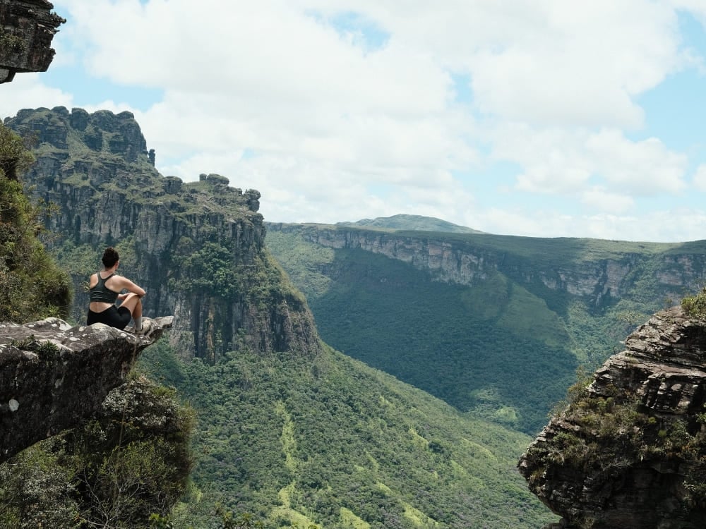 Hiker sitting on a rocky cliff overlooking the green canyons of Chapada Diamantina National Park in Brazil. Hiker sitting on a rocky cliff overlooking the green canyons of Chapada Diamantina National Park in Brazil.
