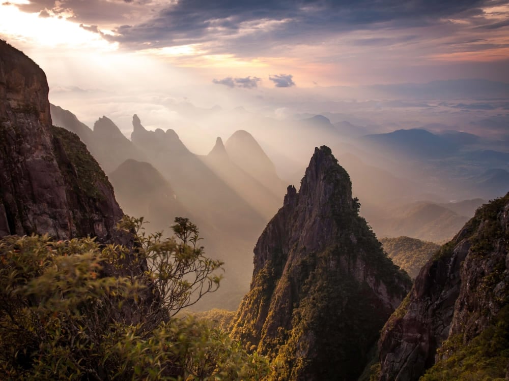 Misty sunrise over the jagged mountain peaks and trails of Serra dos Órgãos National Park in Brazil. Misty sunrise over the jagged mountain peaks and trails of Serra dos Órgãos National Park in Brazil.