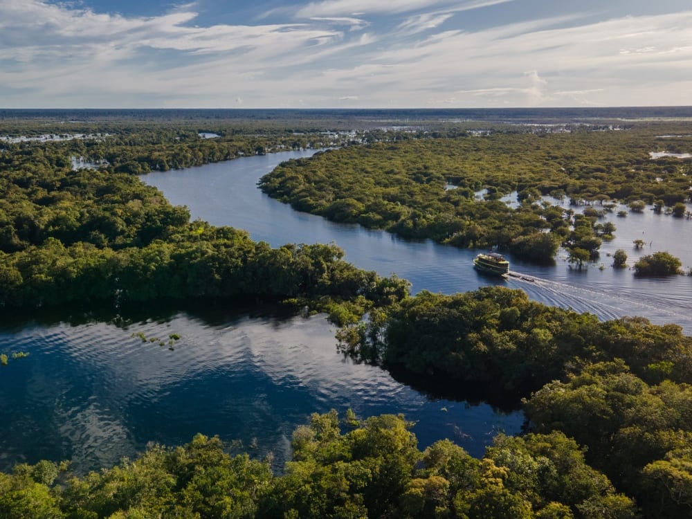 Un barco fluvial navegando por las aguas sinuosas del río Amazonas rodeado de selva exuberante. Un barco fluvial navegando por las aguas sinuosas del río Amazonas rodeado de selva exuberante.